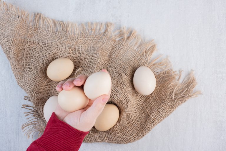 Hand taking eggs from a bundle on a piece of cloth on marble background