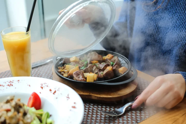 side-view-woman-opened-lid-fried-potatoes-with-liver-frying-pan-stand-with-orange-juice-table